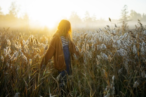 Young woman walking in field at dawn