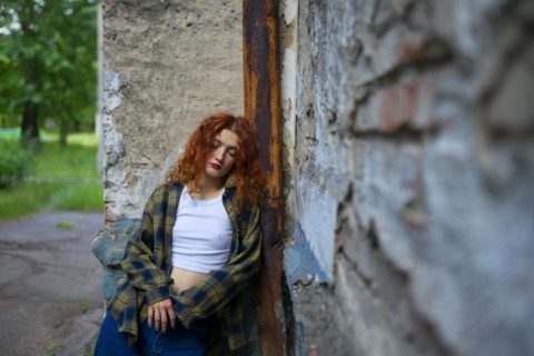 Tired woman with closed eyes leaning on building wall