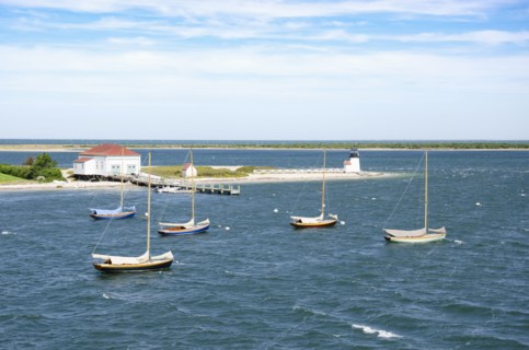 Sailboats anchored in sea near lighthouse and pier, Nantucket, Massachusetts, USA