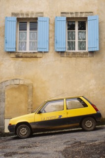 Yellow postal delivery vehicle parked outside a townhouse,  Bonnieux, , France