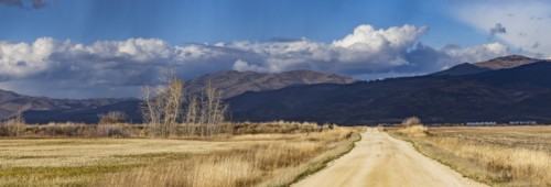 Empty dirt road leading to foothills under stormy skies, Fairfield, Idaho, USA