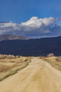 Empty dirt road leading to foothills under stormy skies, Fairfield, Idaho, USA