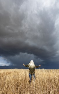 Rear view of woman standing in fall grasses under stormy sky, Fairfield, Idaho, USA