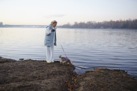 Woman with Yorkshire Terrier on lakeshore, Omsk, , Russia