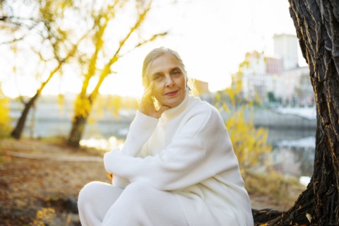 Portrait of woman in white sweater sitting by river in autumn, Omsk, , Russia