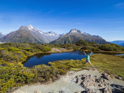 Woman jumping in landscape in Fiordland National Park, Te Anau, Fiordland, New Zealand