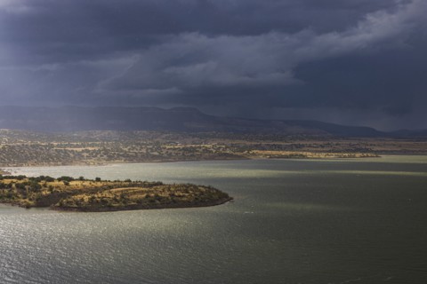 Usa, New Mexico, Abiquiu, Sun shining through storm clouds over Abiquiu Lake, Abiquiu, New Mexico,