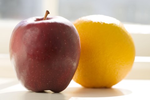 Apple and orange on table in sunlight, Chatham, New Jersey, USA