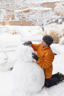 Boy building snowman, Santa Fe, New Mexico, USA