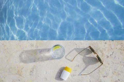 Overhead view of sunglasses, sun cream and drink by pool, , St. John, US Virgin Islands