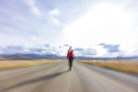 Rear view of woman walking on rural road, blurred motion, Bellevue, Idaho, USA