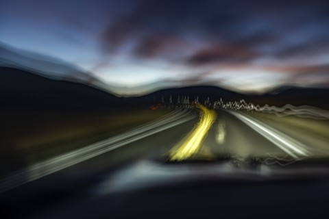 Blurred rural highway seen from moving car at dusk, Buttonwillow, California, USA