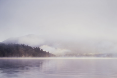 Morning mist rising over calm Lake Placid 
St. Armand, New York, USA