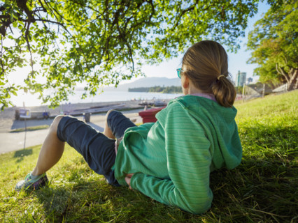 Rear view of woman sitting on lawn near coast
Vancouver, British Columbia, Canada