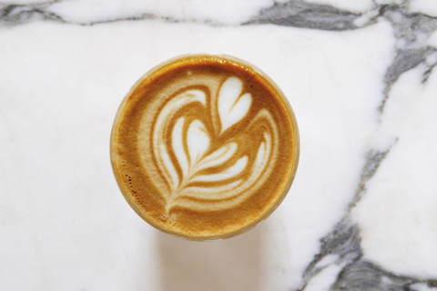 Overhead view of coffee with foam latte art on marble surface
New York City, NY USA