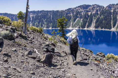 USA, Oregon, Rear view of woman hiking near calm Crater lake