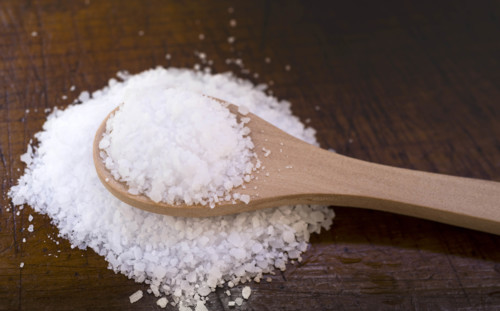 White coarse salt on wooden kitchen spoon