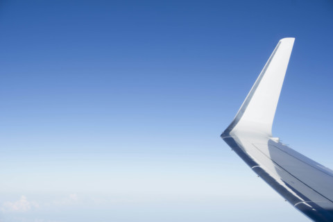 Jet airplane wing against clear blue sky