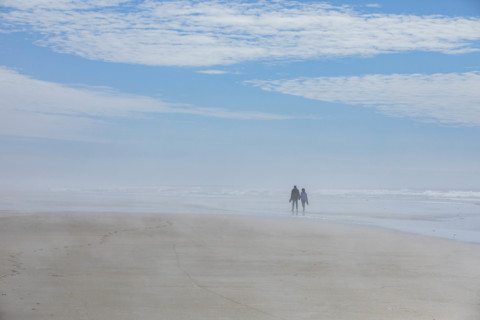USA, Oregon, Newport, Rear view of couple walking on empty beach