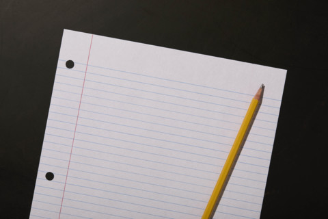 Lined paper and pencil on black background