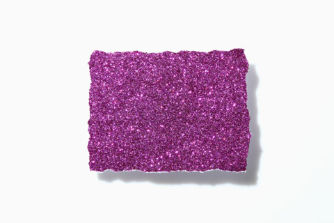 Torn pink glitter paper on white background