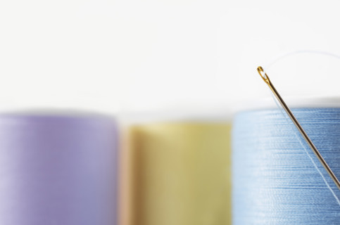 Studio shot of needle and colorful spools of threads