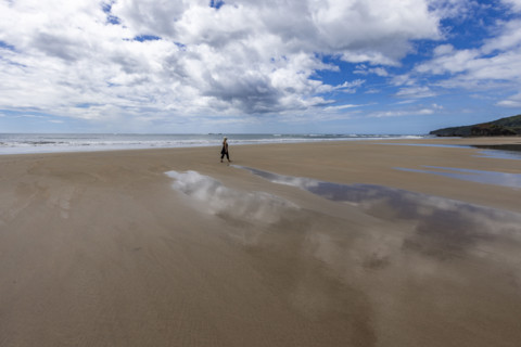 Costa Rica, Guanacaste, Playa Grande, Woman walking on empty beach at low tide