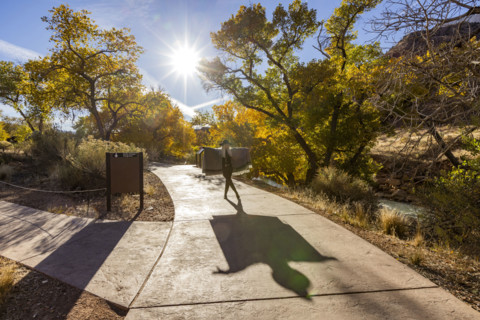 USA, Utah, Zion National Park, Senior woman in poncho making shadows on park walkway