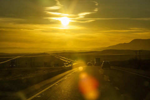 USA, California, Baker, Traffic on interstate highway through desert at sunset