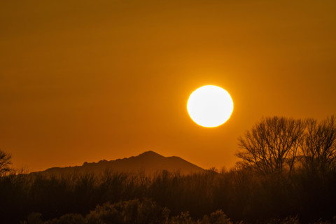 Sun setting above hills against orange sky. Bellevue, Idaho, USA.