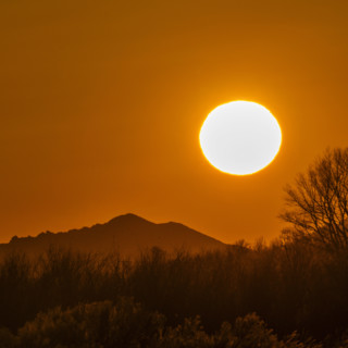 Sun setting above hills against orange sky. Bellevue, Idaho, USA.