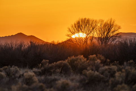 Sun setting above hills against orange sky. Bellevue, Idaho, USA.