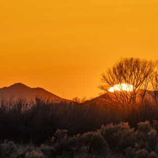 Sun setting above hills against orange sky. Bellevue, Idaho, USA.