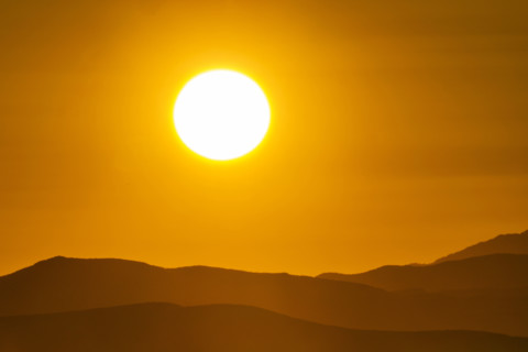 Sun setting above hills against orange sky. Bellevue, Idaho, USA.