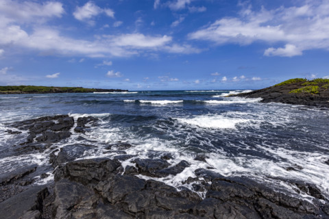 Motion blurred ocean waves washing coastal rocks. Kona, Hawaii, USA.