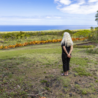 Rear view of woman standing in garden, facing ocean. Kona, Hawaii, USA.