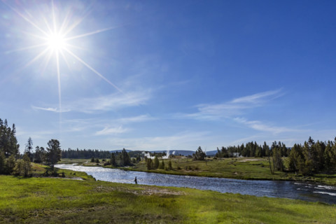 Sun on blue sky over Firehole River . , Wyoming, USA.