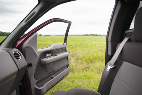Grassy field seen out pickup truck open door. Vergennes, Vermont, USA.