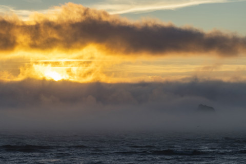 Sunset over fog bank covering sea. Cove Beach, Oregon, USA.