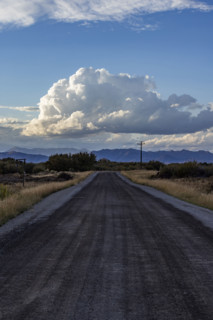 White puffy clouds over empty rural road and mountains. Bellevue, Idaho, USA.