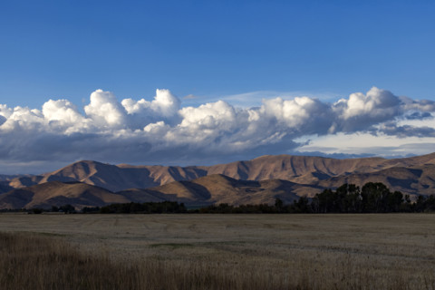White puffy clouds over mountains and field. Bellevue, Idaho, USA.