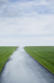 Single lane road crossing green field. Sussex, New Jersey, USA.