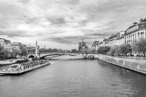 Sightseeing boat on Seine River at Ile Saint-Louis, black and white. Paris, Ile de France, France.