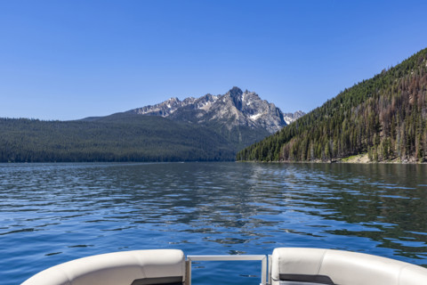 View over prow of boat on Redfish Lake towards Sawtooth Mountains. Stanley, Idaho, USA.