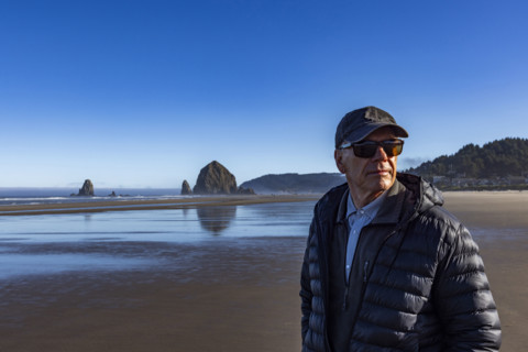 Portrait of senior man on beach with Haystack Rock in background. , Oregon, USA.