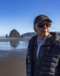 Portrait of senior man on beach with Haystack Rock in background. , Oregon, USA.
