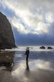 Senior blonde woman next to Haystock Rock. , Oregon, USA.