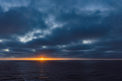 Dark clouds and sun stetting above ocean. La Jolla, California, USA.