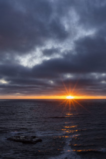 Dark clouds and sun stetting above ocean. La Jolla, California, USA.