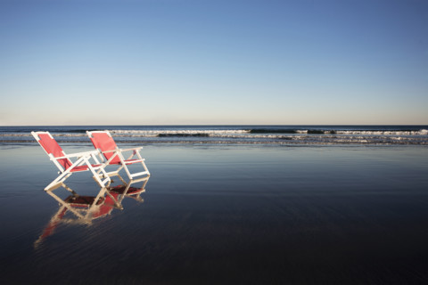 Two beach chairs reflected in wet sand. York, Maine, USA.